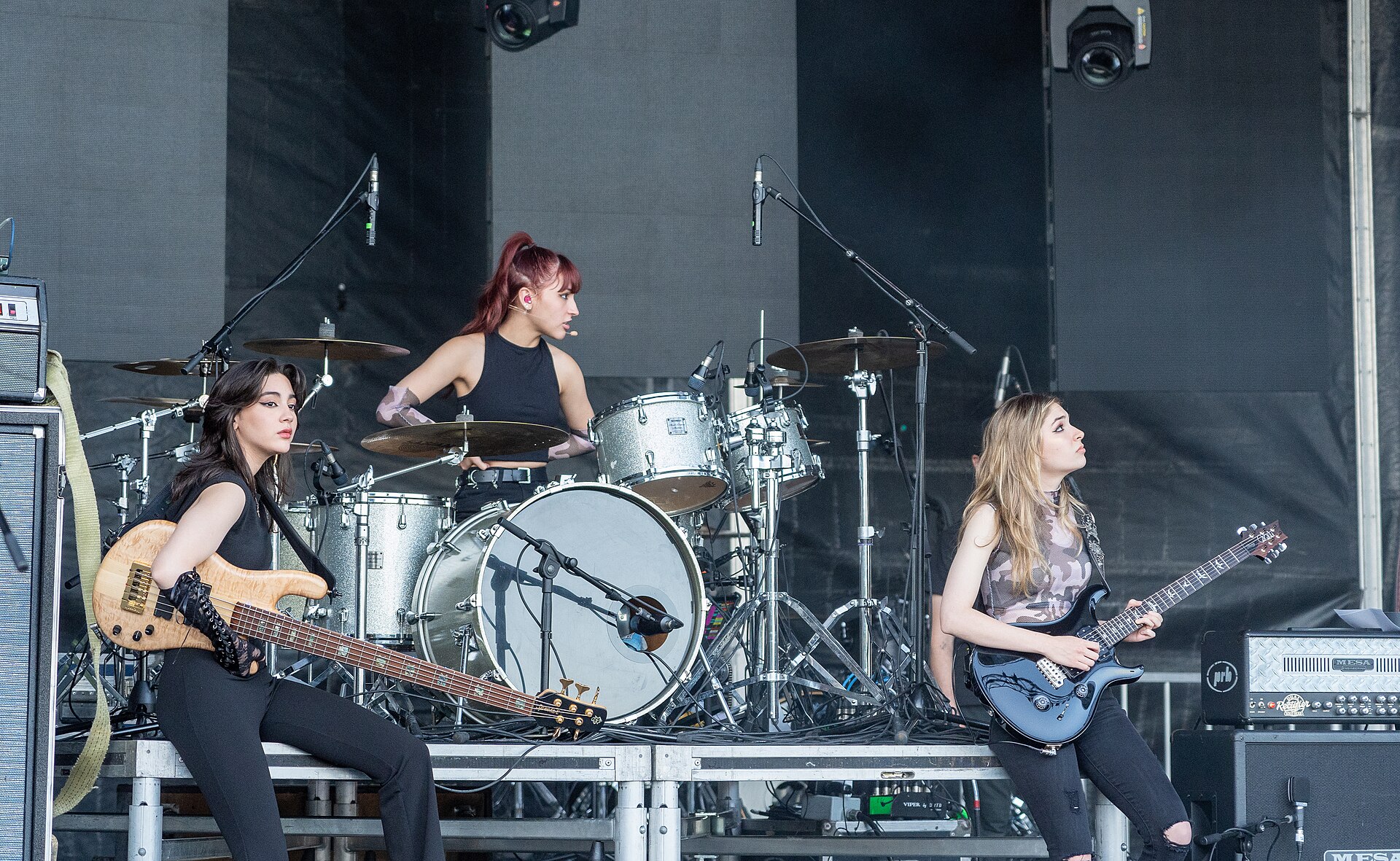 The Warning en concierto: las hermanas Villarreal tocan bajo, batería y guitarra sobre un escenario iluminado