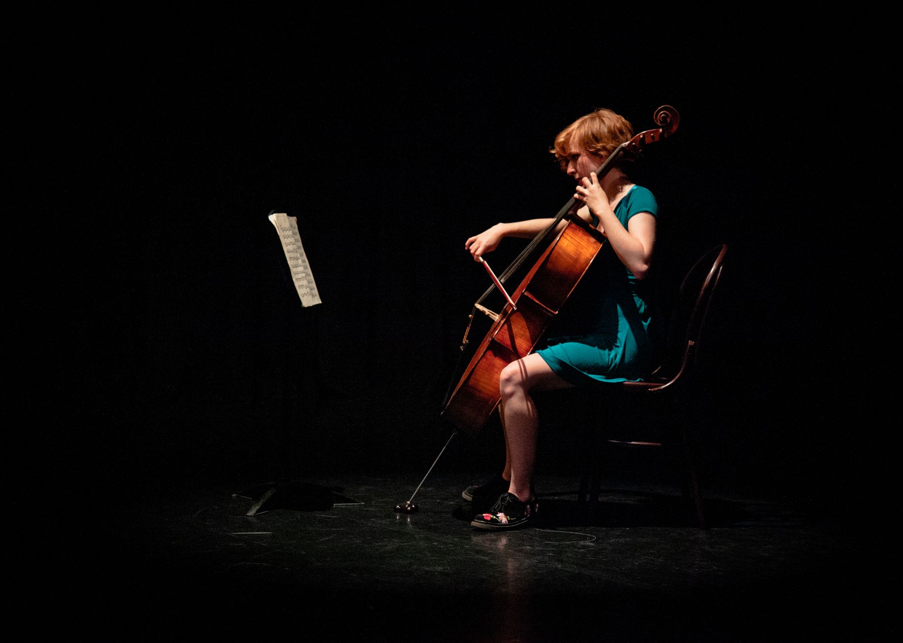 Apocalyptica certificaciones: mujer tocando el violonchelo en un escenario poco iluminado