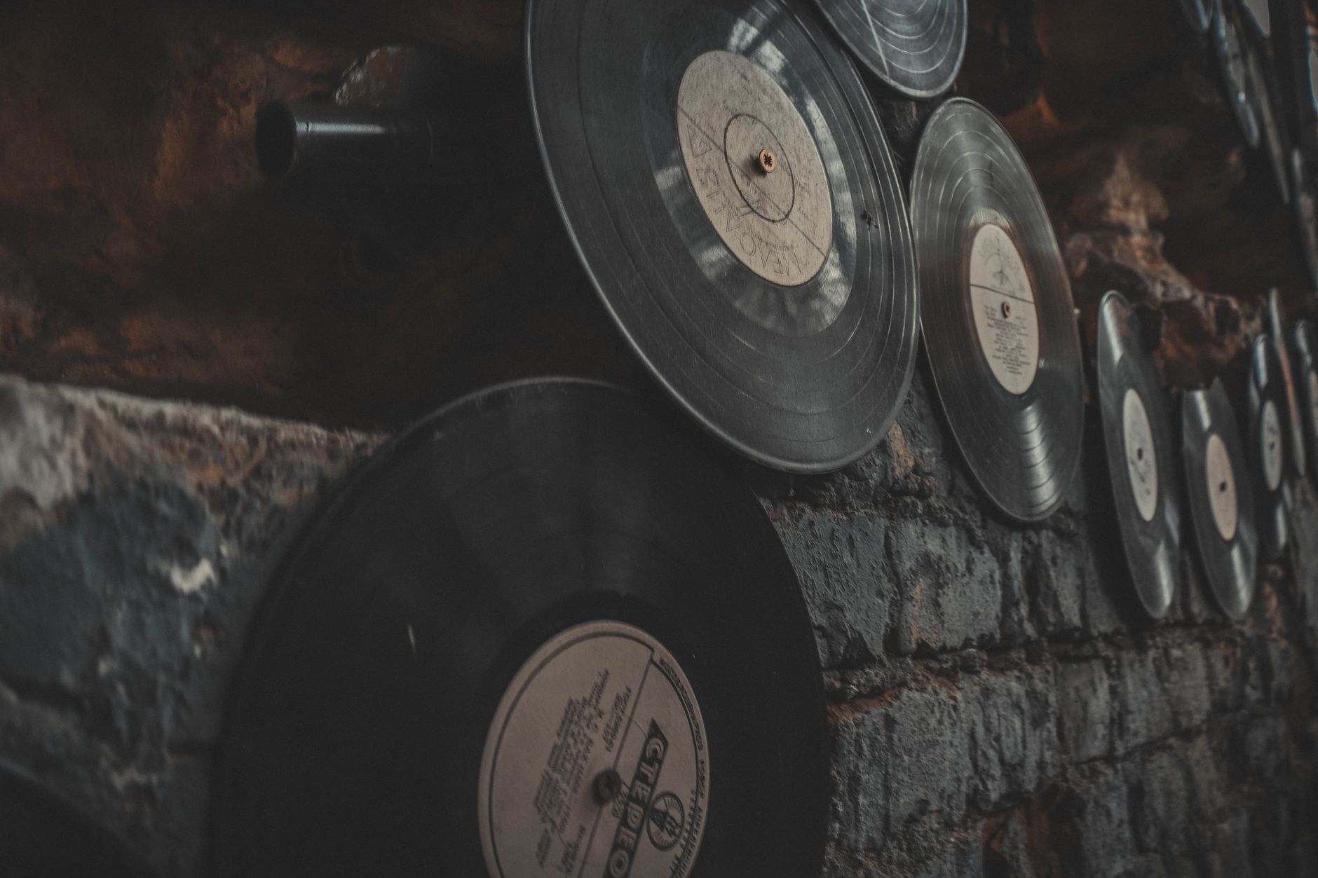 Discos de vinilo en una pared de ladrillo, imagen de referencia del álbum Love Kills! de Induction