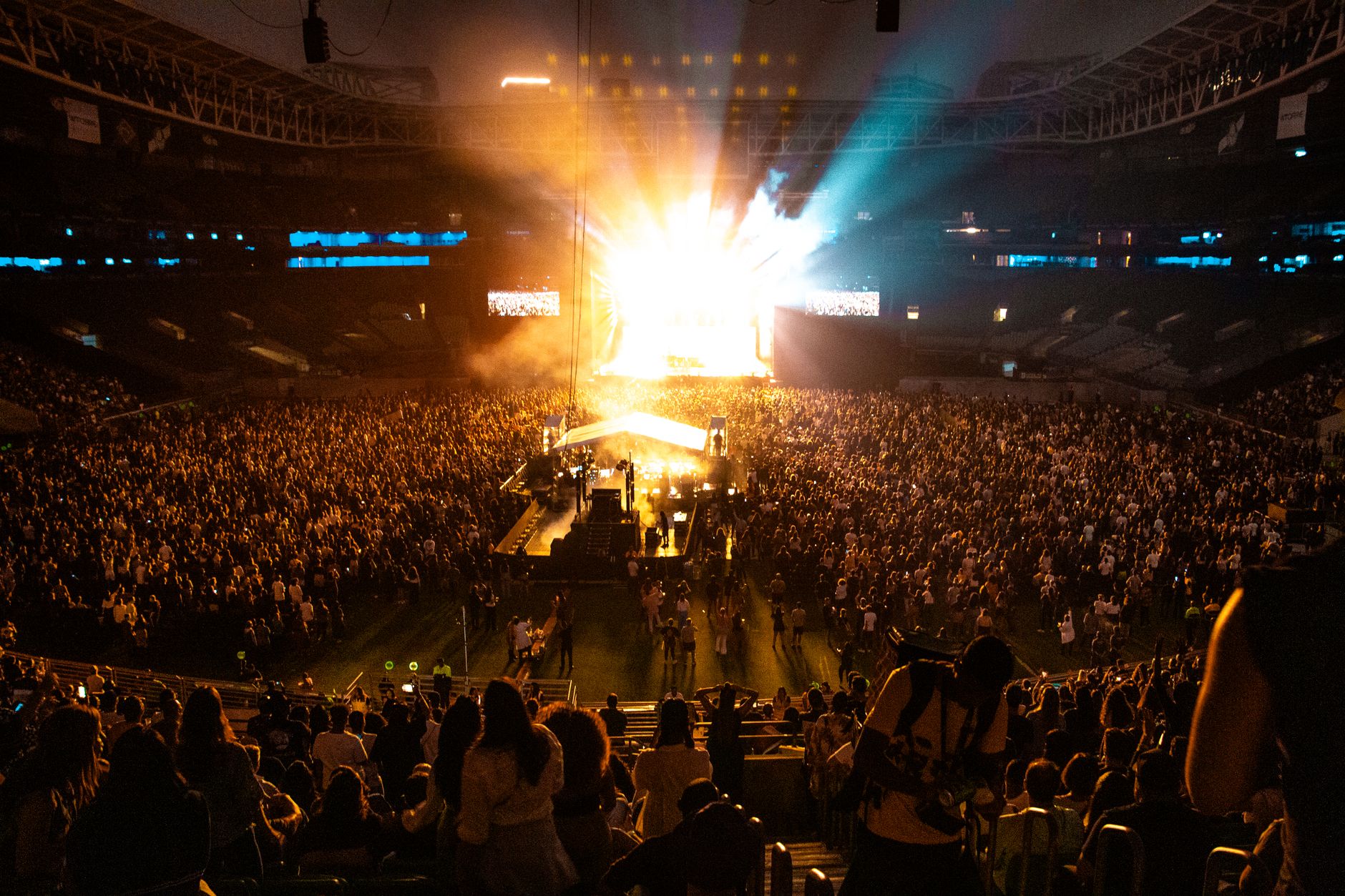Público con luces de escenario en un concierto de estadio, como el show de System of a Down con Pierce the Veil